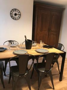 a wooden table with chairs and wine glasses on it at Le Gîte du Jard in Épernay