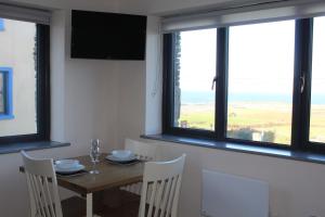 a dining room with a table and chairs and windows at The Stable Self Catering Cottage @ Cappa House BnB in Eyeries