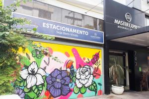 Master Express Moinhos de Vento في بورتو أليغري: لوحة جدارية على جانب مبنى به زهور