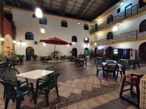 ein leeres Restaurant mit Tischen, Stühlen und einem Regenschirm in der Unterkunft Hotel Doralba Inn in Mérida