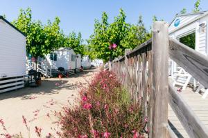 a wooden fence next to a yard with houses and flowers at Camping Tucan - Mobile Homes by Lifestyle Holidays in Lloret de Mar