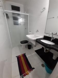 a bathroom with a sink and a toilet and a mirror at Kitnet Guarujá Pitangueiras (sem garagem) in Guarujá