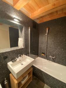 a bathroom with a white sink and a bath tub at Montagne Alternative in Orsières