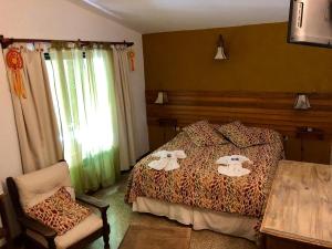 a bedroom with a bed and a table and a chair at Hotel Complejo Najul Suites-Solo Adultos in Mina Clavero