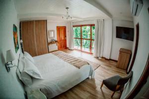 a bedroom with a white bed and a large window at Botánica Iguazú The House Experience in Puerto Iguazú