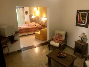 uma sala de estar com uma cama, uma cadeira e uma mesa em Hotel Complejo Najul Suites-Solo Adultos em Mina Clavero