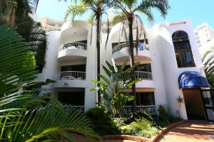 a white building with palm trees in front of it at St Tropez Resort in Gold Coast