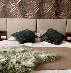 a bed with two green pillows and a furry blanket at Comfort Deluxe Flat in Ruse