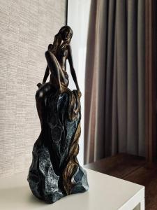 Una statua di bronzo di una donna seduta su una roccia. di Comfort Deluxe Flat a Ruse