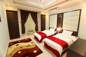 Habitación de hotel con 2 camas y alfombra en سكنا للشقق الفندقية en Buraidah