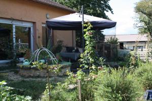 a garden with a blue umbrella in a yard at Au bois de mon coeur in Foameix