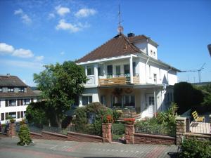 een wit huis met een veranda en een balkon bij Hotel Schloessmann Garni in Bad König