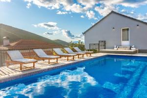 a pool with lounge chairs next to a house at Villa Marija with heated pool in Trilj