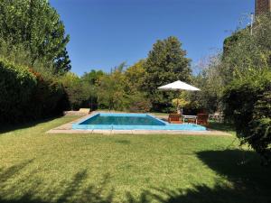 a swimming pool in a yard with an umbrella at Casa Drummond in Ciudad Lujan de Cuyo