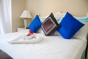 a white bed with blue pillows and a doll in a towel at Fisherman Point Beach Resort in Ocho Rios +18 photos