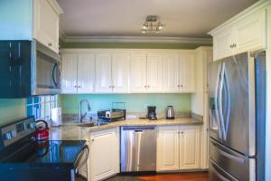 a kitchen with white cabinets and a stainless steel refrigerator at Fisherman Point Beach Resort in Ocho Rios