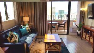 uma sala de estar com um sofá e uma mesa em Waikiki Kuhio 1-bedrm Apt, Ocean view, Free Parking & Wifi em Honolulu