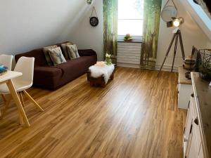 a living room with a brown couch and wooden floors at Pension Haus am Wald in Braunlage