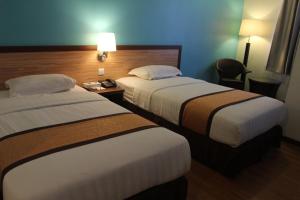 Habitación de hotel con 2 camas y mesa con lámpara en TD Lodge Kota Belud, en Kota Belud