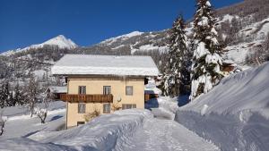 ein schneebedecktes Gebäude mit Bäumen und Bergen in der Unterkunft Haus Leng in Heiligenblut