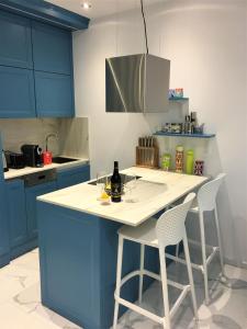 a kitchen with blue cabinets and a white island with two chairs at Duplex Seaview Condo in Durrës