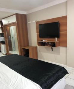 a bedroom with a bed and a flat screen tv at Ponta Negra Flat 811 in Natal