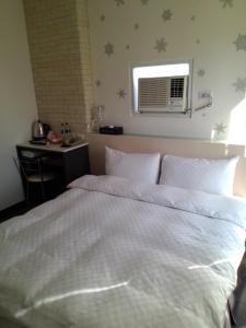 a bedroom with a large white bed with a window at Tilon Hotel in Pingtung City
