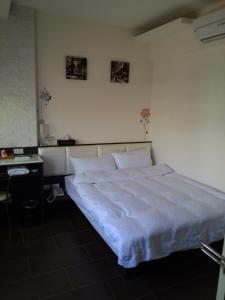 een slaapkamer met een groot bed met witte lakens bij Tilon Hotel in Pingtung City