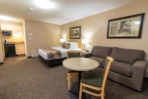 a hotel room with a bed and a couch and a table at BCMInns - Fort McMurray - Rusty's in Fort McMurray