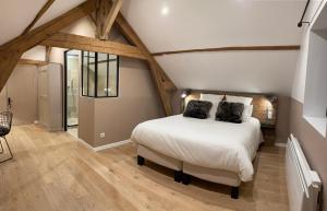 Schlafzimmer mit einem weißen Bett und Holzböden in der Unterkunft L'Atelier des Magnolias in Aumont