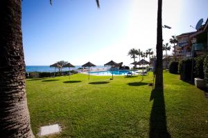 einen Park mit Pool und Meer in der Unterkunft Apartamento Lubina del Sol. 1ª linea de playa - By the Sea in Mijas Costa