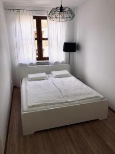 a white bed in a bedroom with a window at Apartament Black & White Wczasowa in Ustka