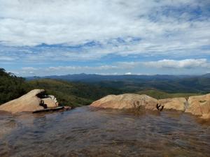 un grupo de personas sentadas sobre una roca en el agua en Pousada do Canto, en Rio Acima