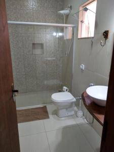 y baño con ducha, aseo y lavamanos. en Pousada Bougainville en Três Corações