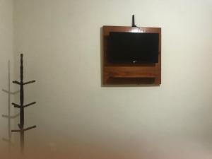 a tv on a wall with two crosses on it at Pousada Bougainville in Três Corações +11 photos