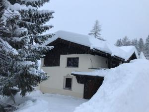 a house covered in snow next to a tree at Davosblick in Davos