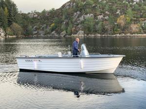 un hombre de pie en un barco blanco en un lago en 8 person holiday home in Urangsv g, en Steinsbø