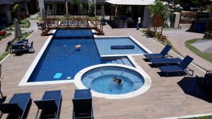 a person swimming in a swimming pool with chairs in a pool at Village Praia do Surf, Itacimirim - Camaçari, BA in Itacimirim