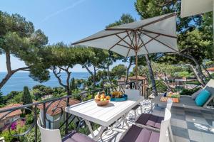 una mesa y sillas en un balcón con sombrilla en Appartement Mera Cosy apartment with incredible sea view en Èze