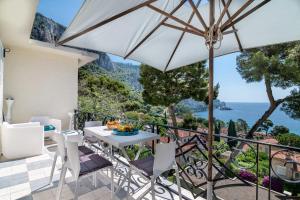 a patio with a table and chairs and an umbrella at Appartement Mera Cosy apartment with incredible sea view in Èze