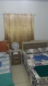 een slaapkamer met 2 bedden en een ventilator op een nachtkastje bij Hospedagem Flor de Araca in Ibicoara