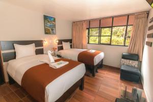 a hotel room with two beds and a window at Samananchis Machupicchu in Machu Picchu