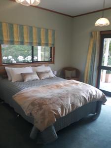 a bedroom with a bed with pillows and a window at Rural Palms in Haruru