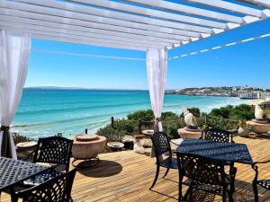a deck with chairs and tables and a view of the ocean at Crystal Lagoon Lodge in Langebaan