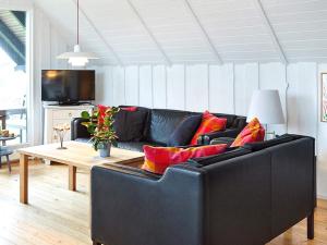 uma sala de estar com um sofá preto e uma mesa em Holiday home Nykøbing Sj XXIX em Ebbeløkke