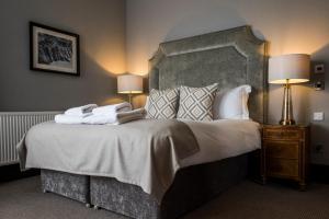 
a hotel room with a bed, chair, and nightstand at Kinnettles Hotel & Spa in St. Andrews
