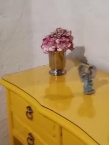 a vase with flowers on top of a yellow dresser at Estancia El Sol in Sogamoso