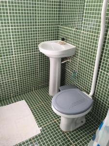 a green tiled bathroom with a toilet and a sink at João de Barro Hospedagem in Caeté-Açu