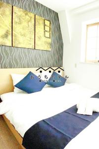 a bedroom with two beds with blue pillows at OUCHI HOTEL Yokogawa in Hiroshima