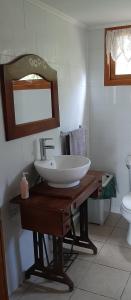 a bathroom with a sink and a mirror and a toilet at Cabañas Emporio de la Meme in San José de Maipo